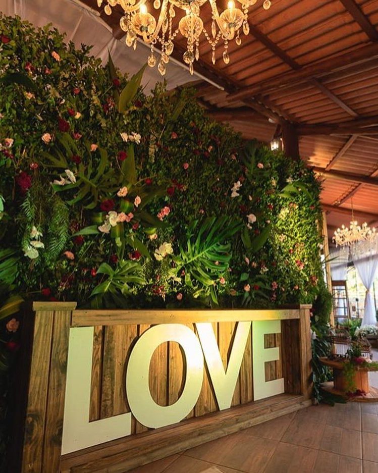 Salão decorado pra casamento, com parede de flores e letreiro LOVE