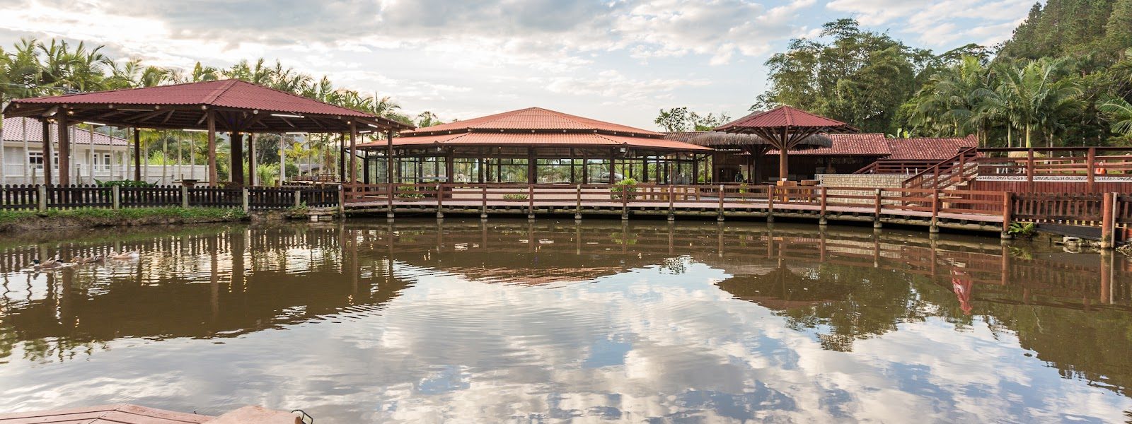 Lago do Eco Park refletindo o céu, com os salões ao fundo