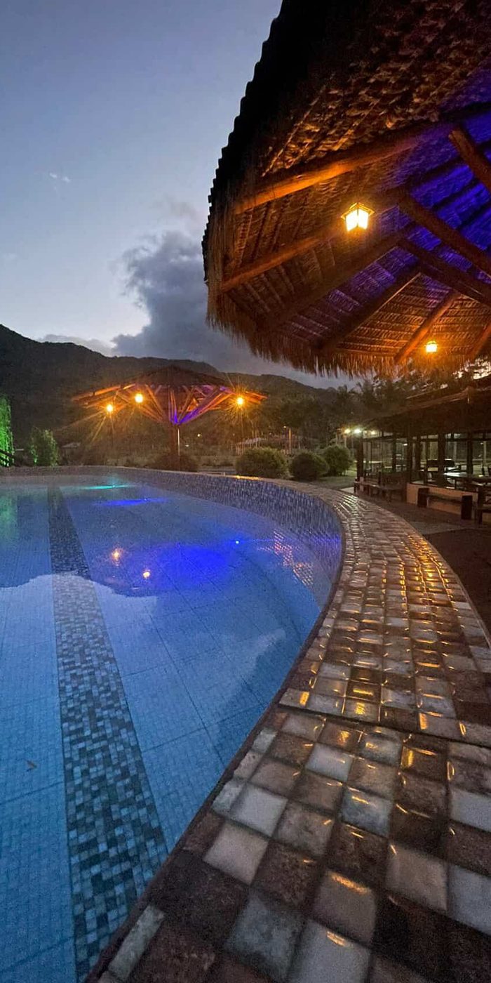 Piscina e quiosque iluminados no fim de tarde
